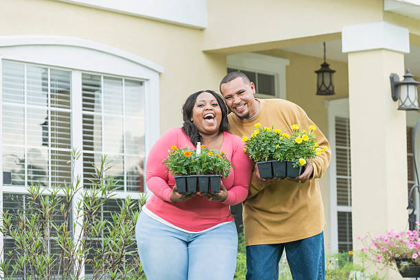 jeune couple noir à l’extérieur de la maison tenant des plateaux de fleurs - heavy plant photos et images de collection