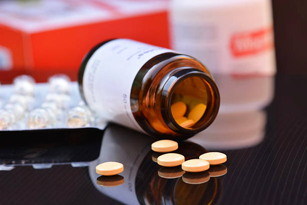 istock Medical pills on a black mirrored background with bright reflect 606635428