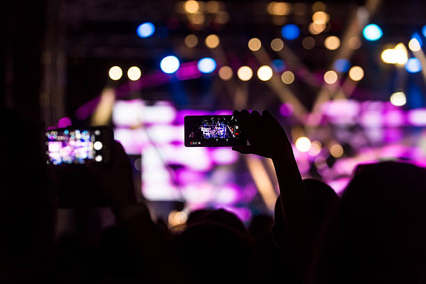istock People taking photographs with touch smart phone during a music 606635444