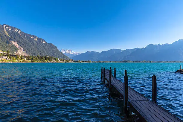Stunning view of Geneva lake, with the peaks Dents du Midi of Swiss Alps in background and a small dock in foreground, Montreux, Canton of Vaud, Switzerland