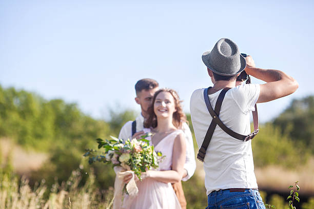 photographer in action a wedding photographer takes pictures of the bride and groom in nature, the photographer in action wedding photography stock pictures, royalty-free photos & images