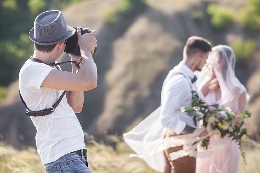 a wedding photographer takes pictures of the bride and groom in nature, the photographer in action