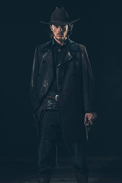 istock Menacing vintage 1900 cowboy standing with revolver. Studio shot 606642870