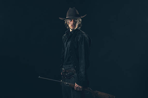 istock Retro 1900 western cowboy standing with rifle. Young man. 606649212