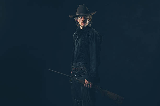istock Retro 1900 western cowboy standing with rifle. Young man. 606649490