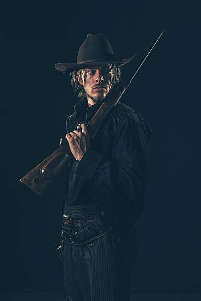 istock Retro 1900 western cowboy standing with rifle. Young man. 606651502