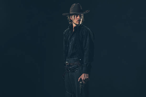 istock Alert vintage 1900 cowboy standing with gun. Studio shot. 606653658