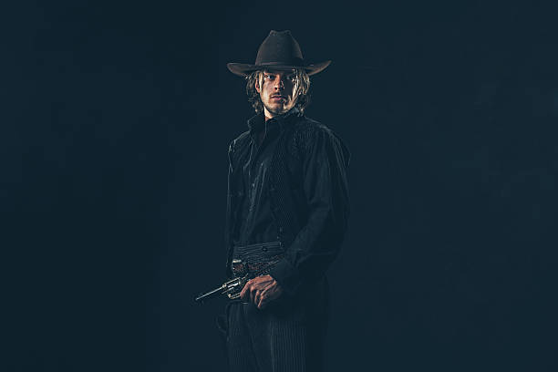 istock Alert vintage 1900 cowboy standing with gun. Studio shot. 606653790