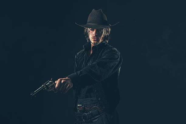 istock Vintage cowboy shooting with gun. Young man. Studio shot. 606654546