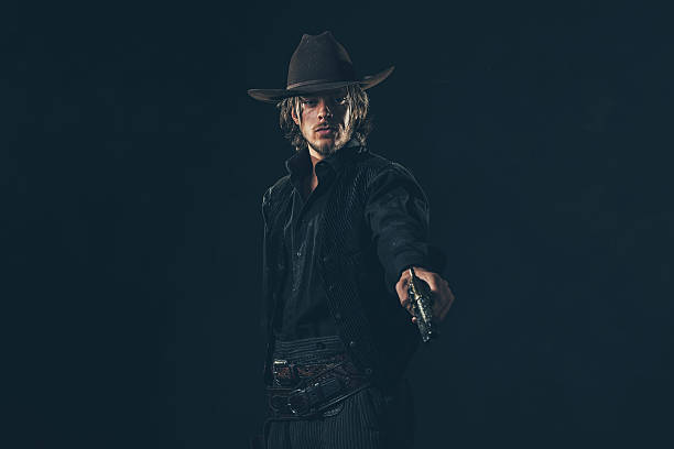istock Vintage cowboy shooting with gun. Young man. Studio shot. 606655096