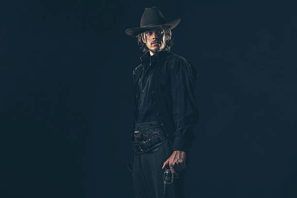 istock Vintage 1900 cowboy. Young man. Studio shot against dark wall. 606655472
