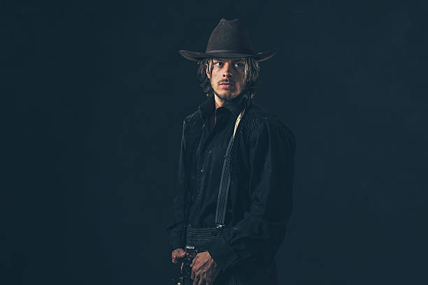 istock Vintage 1900 cowboy. Young man. Studio shot against dark wall. 606656124