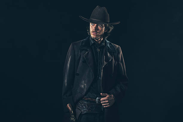 istock Vintage 1900 cowboy. Young man. Studio shot against dark wall. 606658178