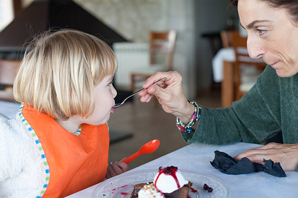 istock woman feeding little kid with spoon chocolate cake 606659510