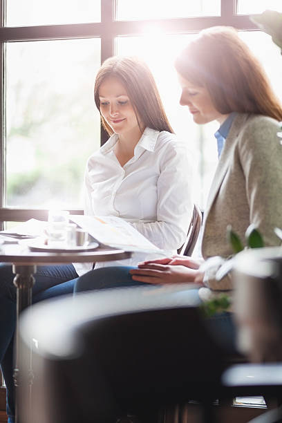 istock Young businesswomen reading brochure at cafe table 606665450