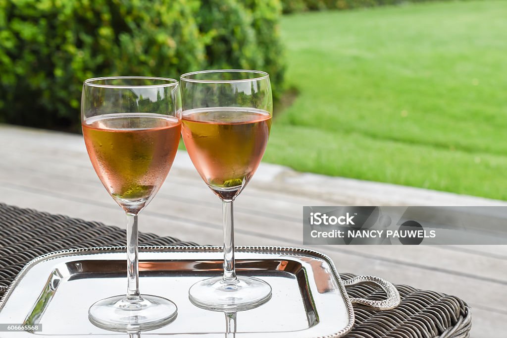Two glasses with cold rose wine Two glasses of chilled rose wine presented on a silver tray with garden background. Serving Tray Stock Photo