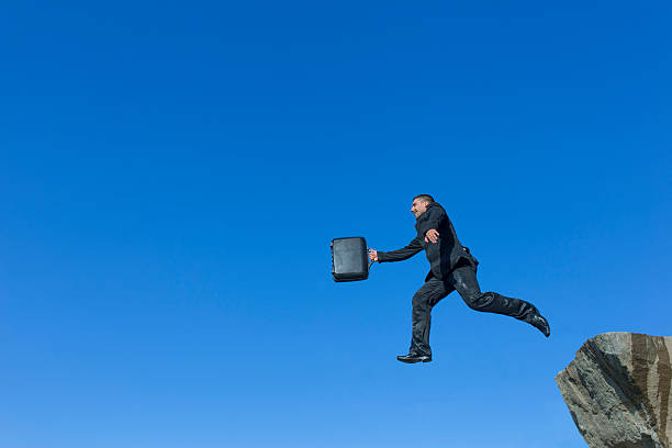 istock Jumping man with a diplomat from a cliff. 606665958