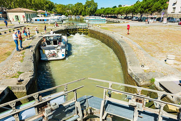 Carcasonne, France - August 3, 2016: a recreational boat inside a river lock at canal du midi in carcasonne. Some people are standind and watching.