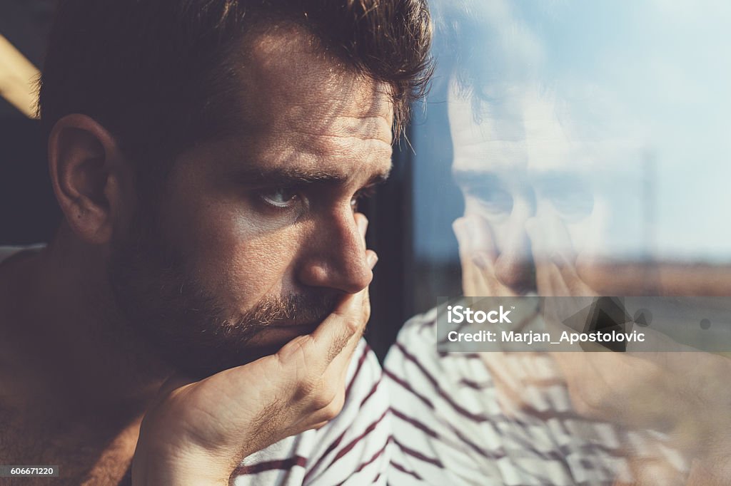 Trauriger junger Mann Blick durch das Fenster - Lizenzfrei Männer Stock-Foto