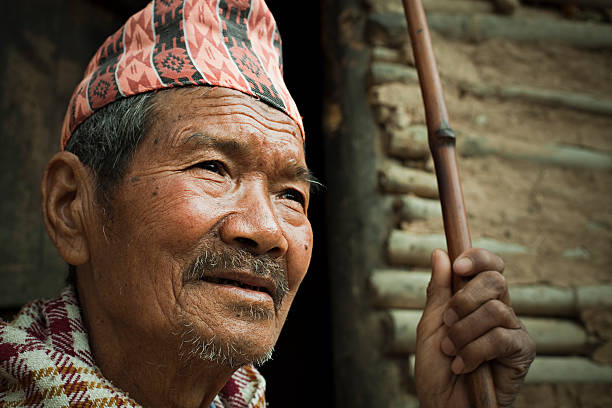 istock Senior Nepalese peasant man with stick near adobe house. 606671820