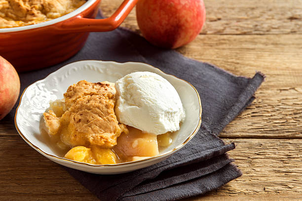 peach cobbler with ice cream Homemade peach cobbler with vanilla ice cream over rustic wooden background - healthy pastry dessert ice pie photography stock pictures, royalty-free photos & images