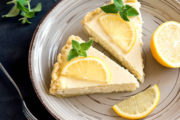 lemon cheesecake Pieces of delicious homemade lemon cheesecake with slices of lemon and mint on plate close up torte photos stock pictures, royalty-free photos & images