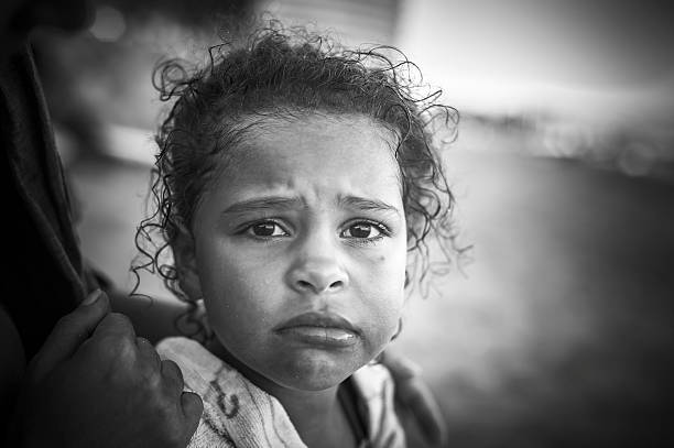 Stock photo of little girl who looks unhappy. She is coming back from a swim in the sea so her hair is wet and she has a towel wrap around her. Image processed into black and white.  This file has a signed model release.