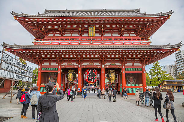 Tokyo, Japan - November 12, 2015:  Asakusa Senso-ji ancient Kannon temple main hall, in Tokyo, Japan. Some tourists are walking around this distinctive red landmark.  Sensō-ji is an ancient Buddhist temple located in Asakusa, Tokyo, Japan. It is Tokyo's oldest temple, and one of its most significant.