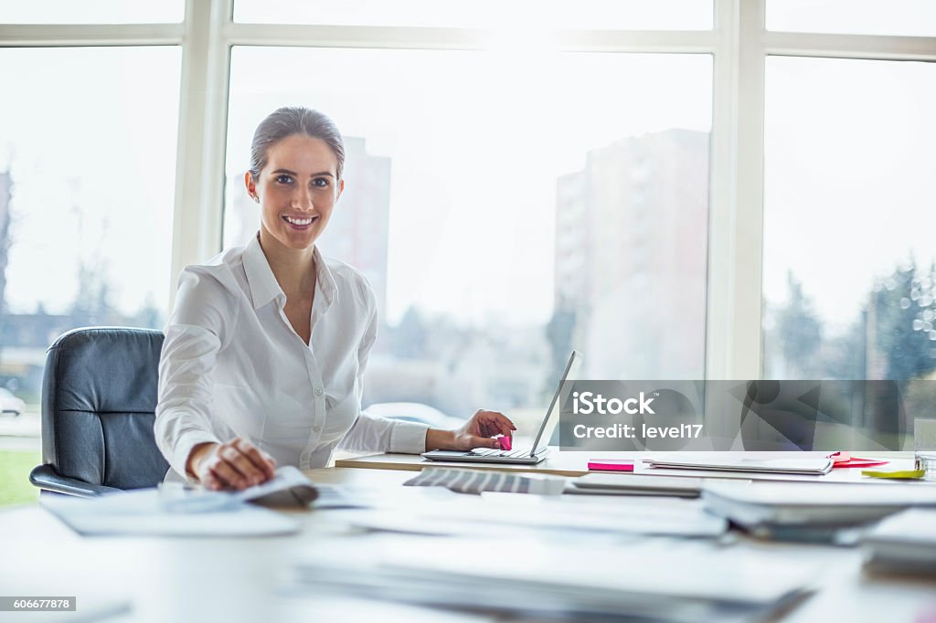 Portrait of happy young businesswoman using laptop at office desk Adult Stock Photo