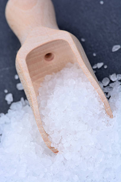 istock White salt in a wooden scoop 606701762