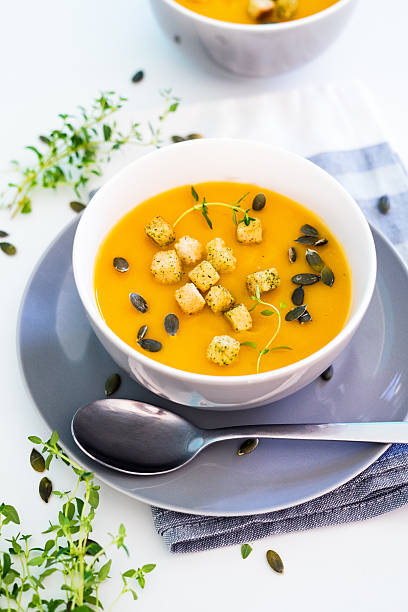 Pumpkin soup served with croutons and pumpkin seeds Pumpkin soup on a white background squash soup stock pictures, royalty-free photos & images