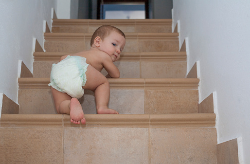 Baby boy crawling up the stairs. Low angle view