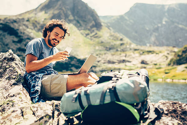 homem mandando sms na montanha - tourist backpack smiling cheerful - fotografias e filmes do acervo