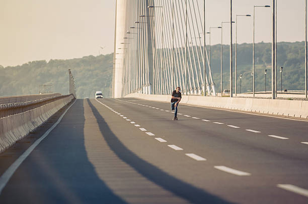 istock Skateboarder riding a skate over a city road bridge 606709008