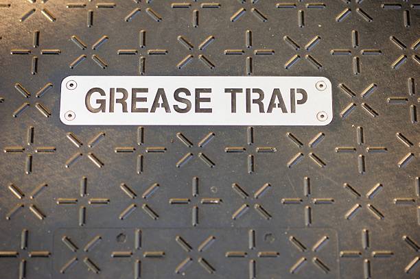 Grease trap sign on cover Close up photograph of stenciled metal great trap sign on metal cover on ground floor plate.  Plate has cross and plus sign pattern. lubrication stock pictures, royalty-free photos & images