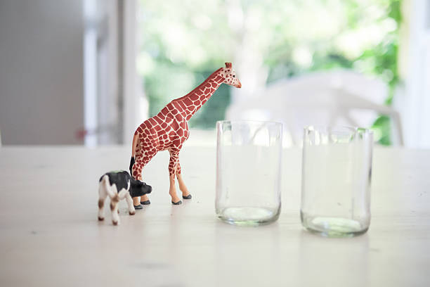 istock Giraffe And Cow Toys By Empty Glasses On Table 606757943