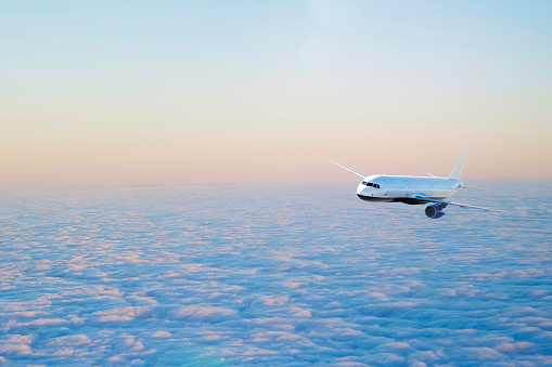 Civil passenger plane in flight. Aircraft flying on a high altitude above the storm clouds during sunset.