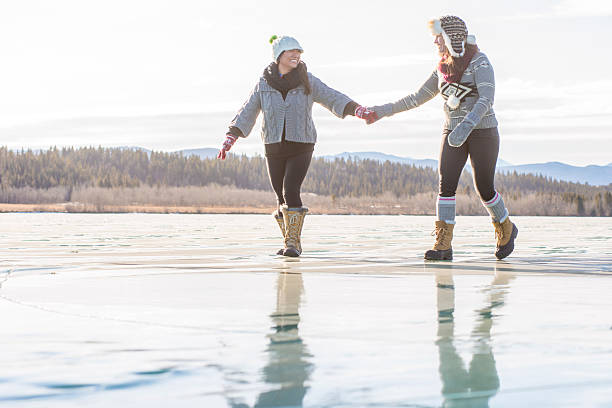 istock Two young women slide along ice, frozen lake 607063799
