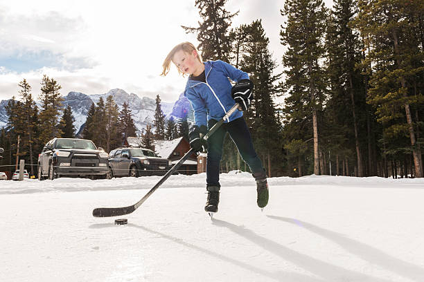istock Young boy palys hockey on commuinty pond,mountains 607063809