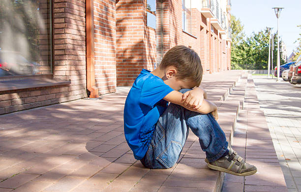 istock Sad, lonely, unhappy, disappointed child sitting alone on the ground 607253502