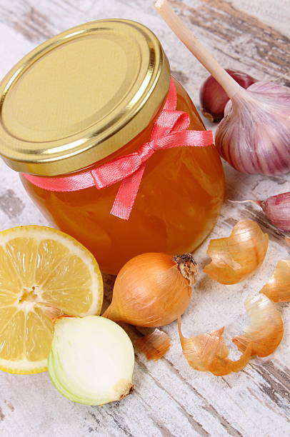 Honey in glass jar, onion, lemon and garlic stock photo