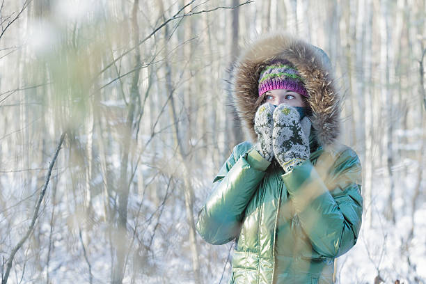 Giovane donna nella foresta invernale nascondendo il viso in guanti - foto stock