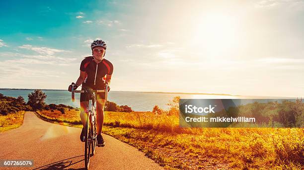 Cyclist Rides Her Bike Up A Steep Hill At Sunset Stock Photo - Download Image Now - Cycling, Sports Race, Cycle - Vehicle