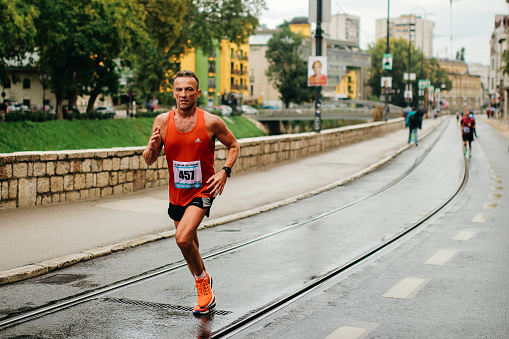 Sarajevo, Bosnia and Herzegovina - September 18, 2016: Mature Marathon Runner leads the competition during the NGO Half Marathon in Sarajevo. Running in the front by himself all alone.