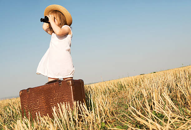 istock Little girl with suitcase is looking trough binoculars 607267622
