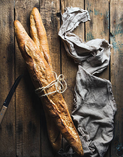 istock Two French baguettes on rough rustic wooden background 607268996