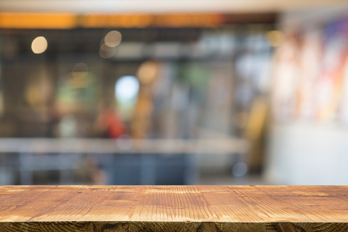 Image of wooden table in front of blurred background. Empty table and blurred public scene.