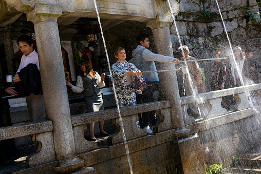 Kyoto, Japan - Nov 6, 2015: Visitors drinking the Holy Water of the Otowa Waterfall at Kiyomizu-dera, Kyoto. The waterfall is divided in three streams and it is said that its water has the power to fulfil the wishes.