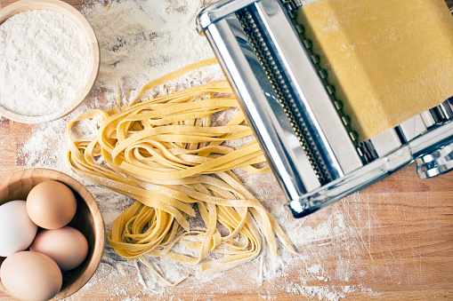 fresh pasta and pasta machine on kitchen table