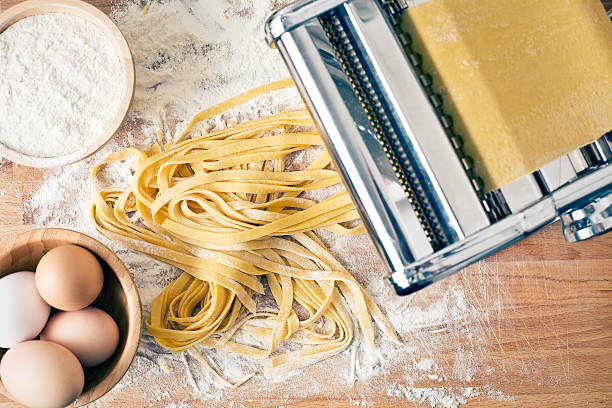fresh pasta and pasta machine fresh pasta and pasta machine on kitchen table pasta stock pictures, royalty-free photos & images
